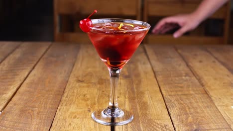 waiter delivering a red fruit cocktail on a wooden table