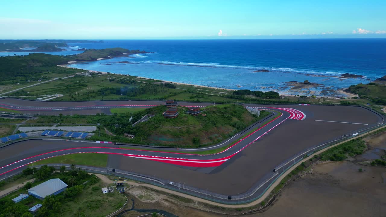 Circuito Internazionale di Mandalika che mostra le sue linee della pista da corsa e gli edifici contro il bellissimo oceano blu. Speed ramp, hyper motion, time lapse. Splendida vista aerea, ampio panorama orbitale.