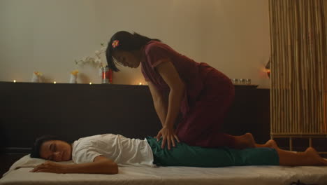mujer asiática realiza masaje tradicional tailandés a una hermosa mujer europea. rehabilitación y tratamiento después de lesiones con la ayuda de masaje. relajarse y descansar de masaje de piernas brazos y espalda. masaje terapéutico