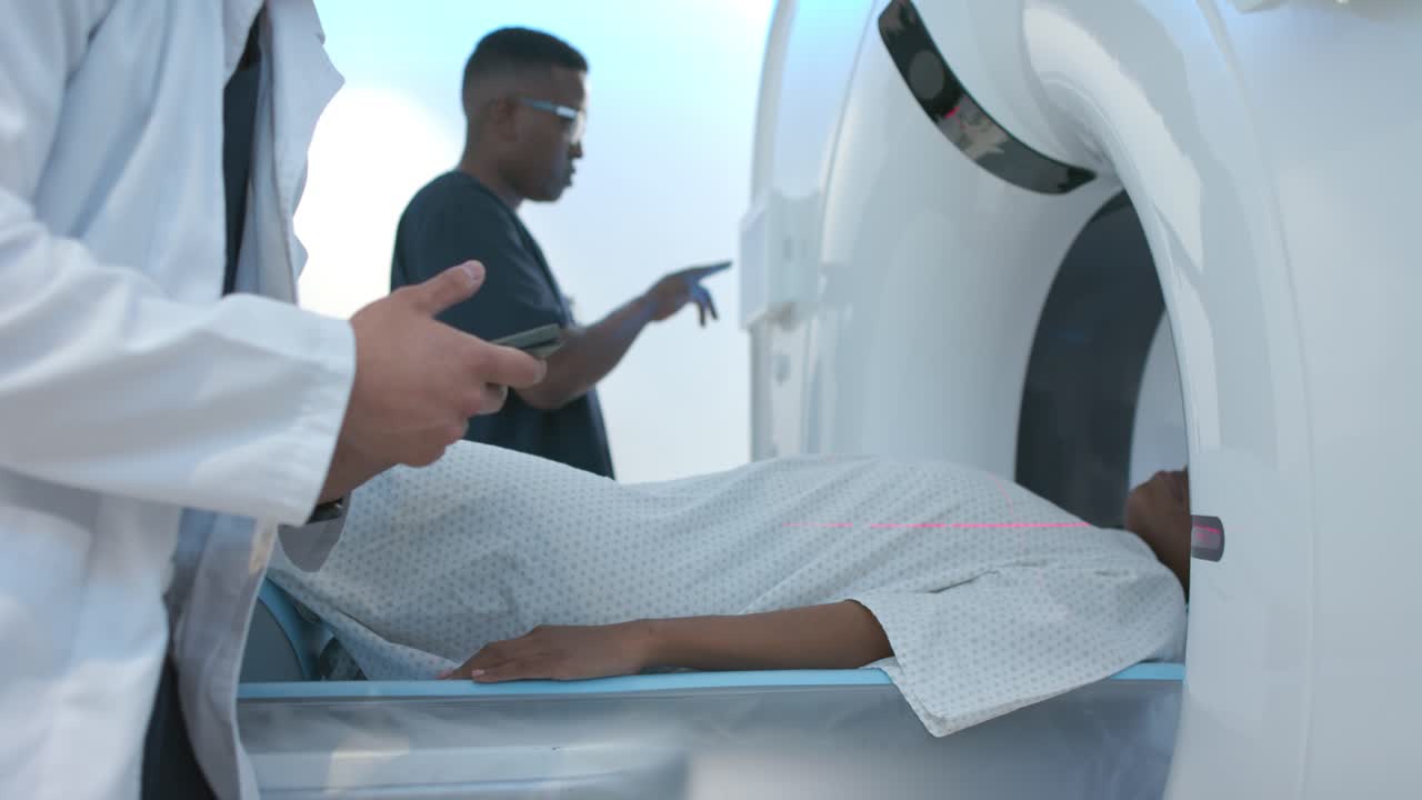 After arrival Diverse techs placing African American woman gowned on scanner aiming laser for scan