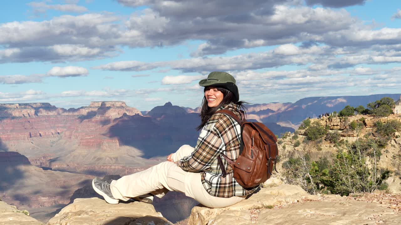 Donna felice seduta sul bordo di un dirupo al Parco Nazionale del Grand Canyon