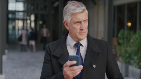 portrait handsome senior businessman executive using smartphone in city texting browsing online messages looking serious mature commuter waiting slow motion