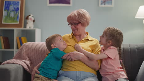 Mature-lady-cuddles-little-grandson-girl-hugs-in-living-room