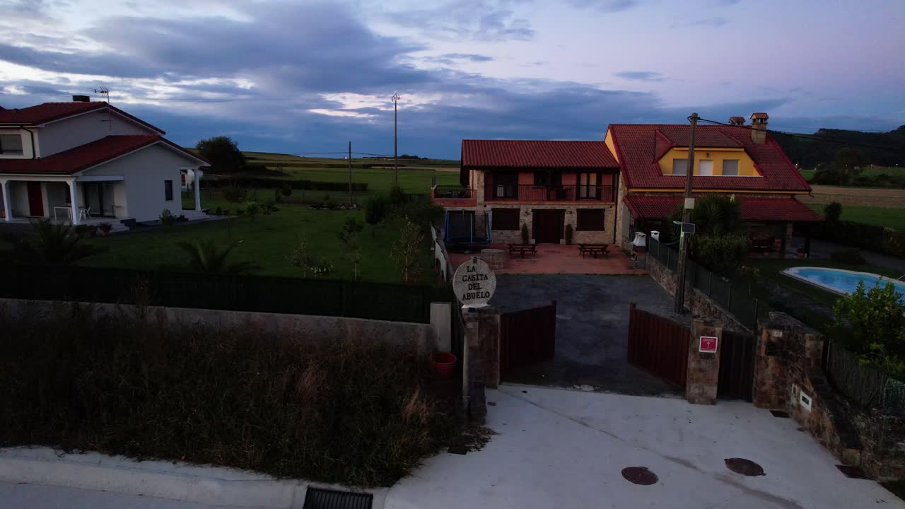 Two rural homes with red roofs and a lush green yard at dusk in Galizano, Cantabria. Aerial