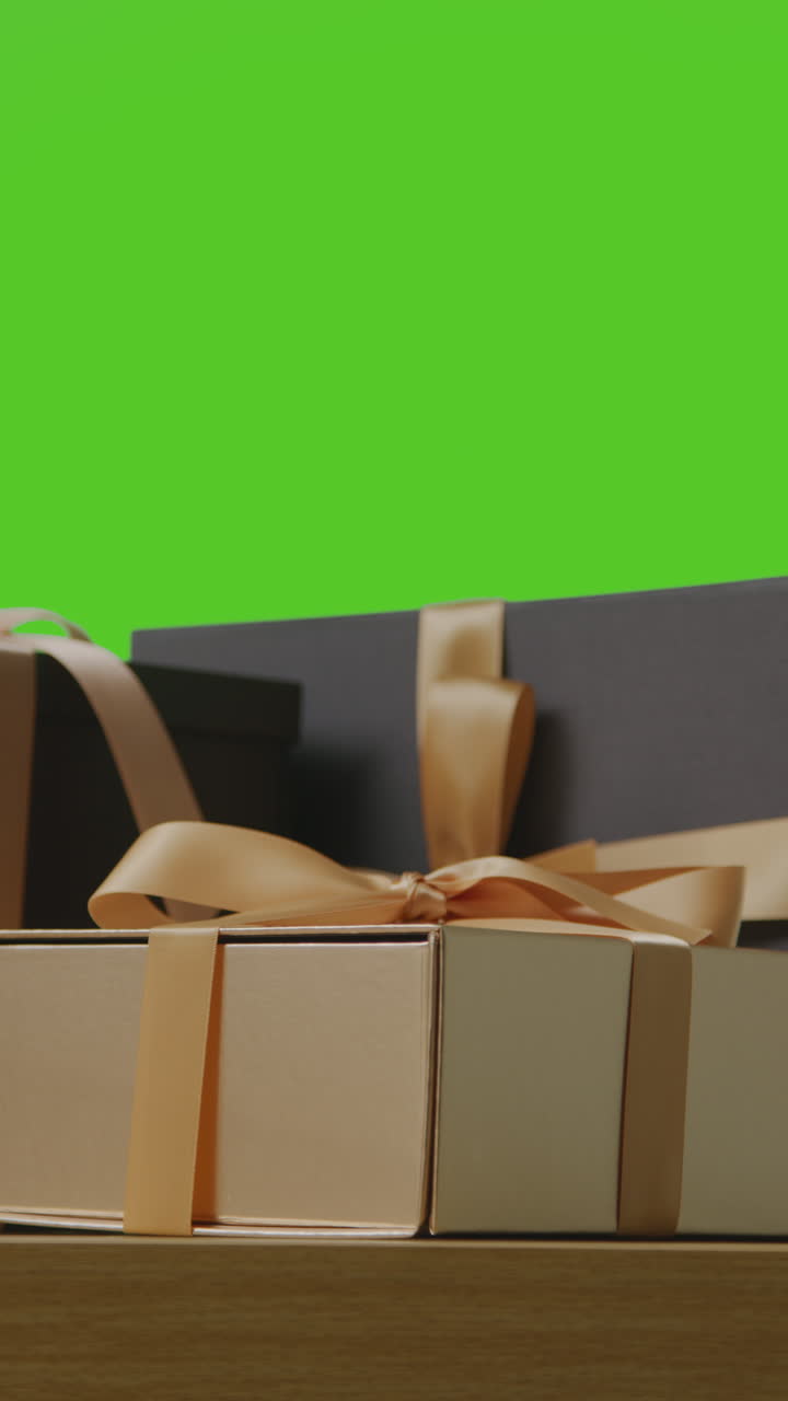 video vertical de regalos en cajas envueltas en regalos decoradas con cinta en la mesa disparado contra la pantalla verde 2