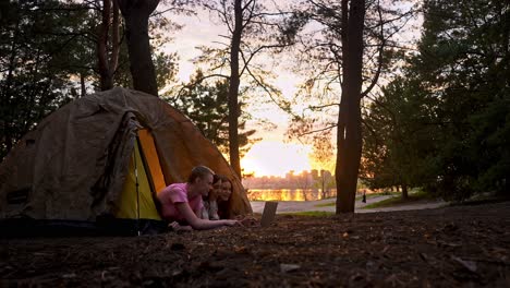 friends camping and using laptop at sunset