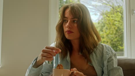 a beautiful woman is deep in thought as she prepares a cup of tea on the couch - close up