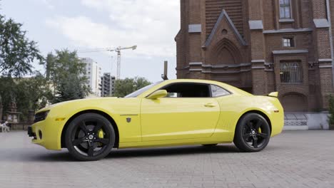 camaro amarillo estacionado frente a una iglesia en la ciudad