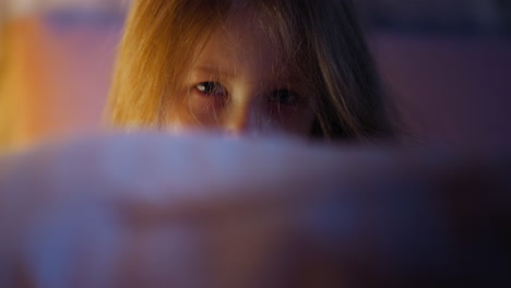 blonde little child looks from behind pillow in bedroom