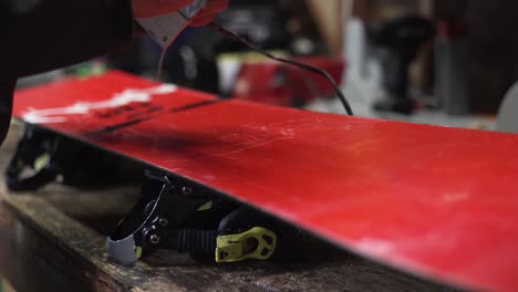 Melting-hot-wax-onto-the-base-of-a-red-snowboard