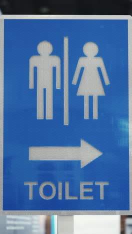 blue toilet sign with male and female symbols and directional arrow