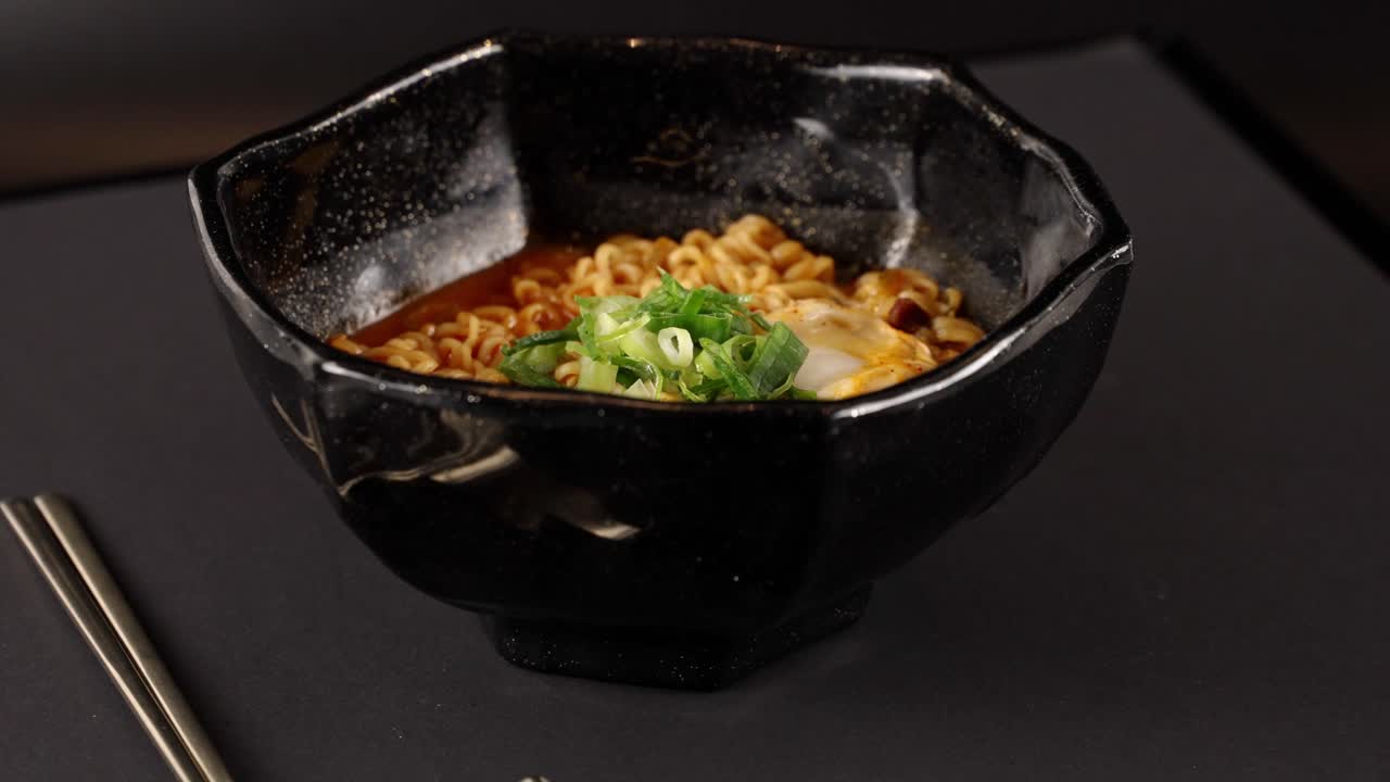 A video of spicy stir-fried ramyun, topped with a soft-boiled egg and scallions. 반숙 계란과 파를 올린 매콤한 볶음라면 영상.
