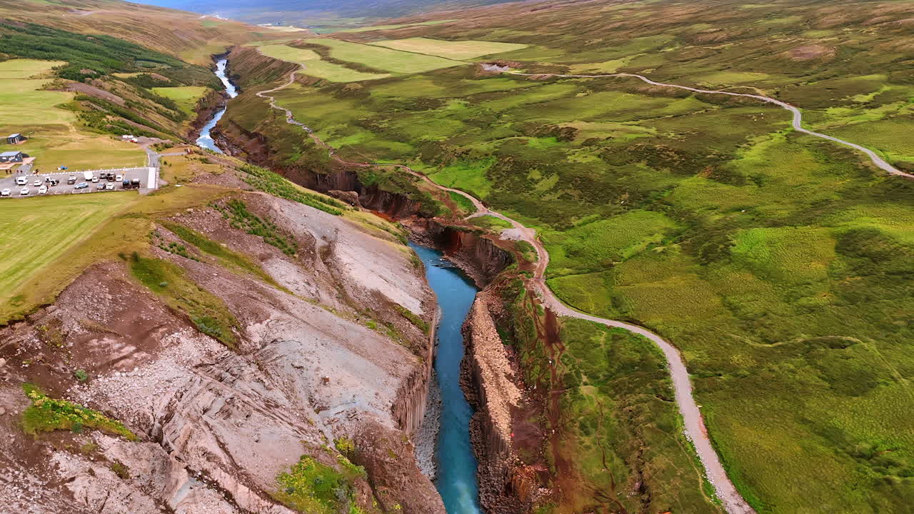 A huge crack in the rocky land where the river flows. Drone footage above the stunning landscape of Iceland.