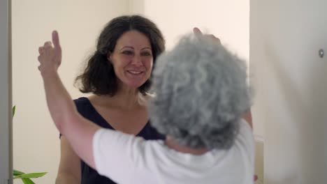 cheerful mature woman bringing products to senior woman.