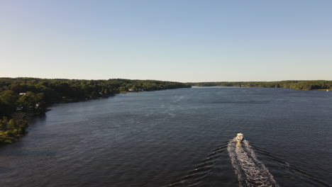 aerial shot of looking down at speed boat on the kennebec river maine, overtaking boat, exits bottom right of frame