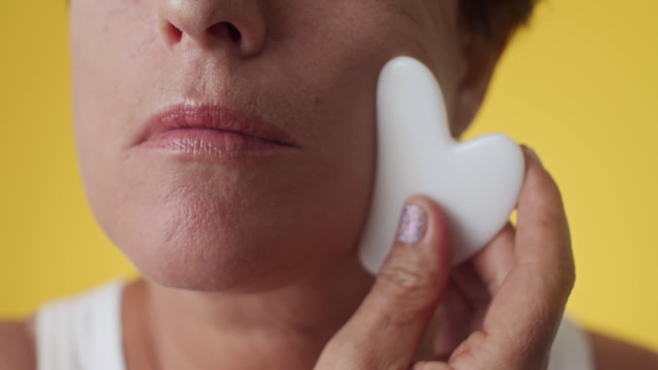 Woman Practicing Facial Massage with Gua Sha on Chin and Cheeks