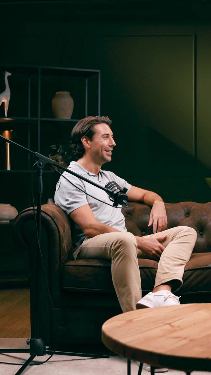 Uomo seduto su divano in pelle che parla durante la registrazione di un podcast