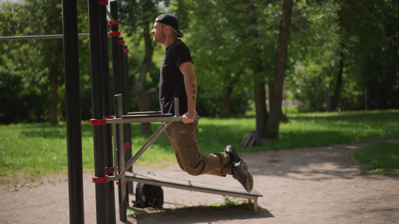 Man Performing Dips Among Green Trees Outdoors, Bodyweight Exercise In Park With Green Surroundings, Individual Engaging In Parallel Bar Dips Amid Nature During Outdoor Fitness Routine