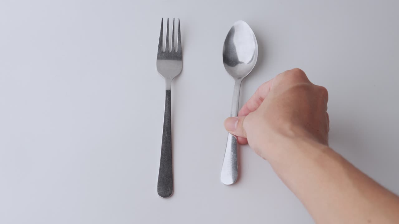 un tenedor y una cuchara colocados sobre un fondo blanco