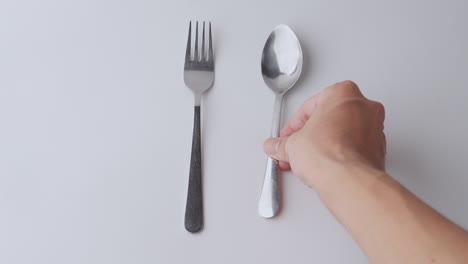 fork and spoon being placed on a white background