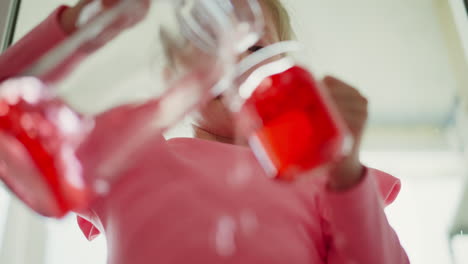 child experimenting with red liquid in jars and cups