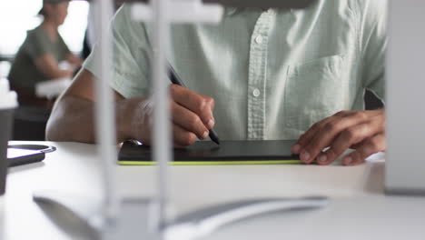 persona dibujando en una tableta digital con un lápiz, centrada en la tarea en un entorno empresarial