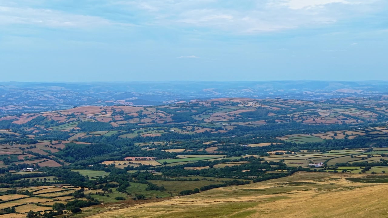 Høytliggende luftfoto av solblekede avlinger og uttørkede, brunsvidde jorder på den britiske landsbygda. Fremhever tørr jord, uttørkede beitemarker og skadede avlinger som følge av langvarige hetebølger og ekstremvær