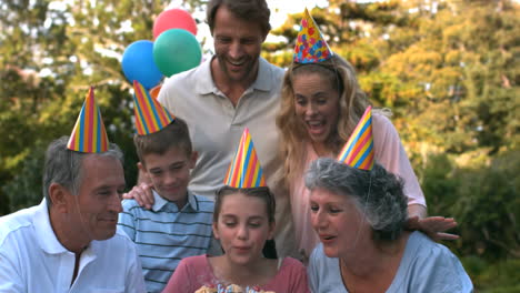 familia feliz soplando las velas del pastel de cumpleaños