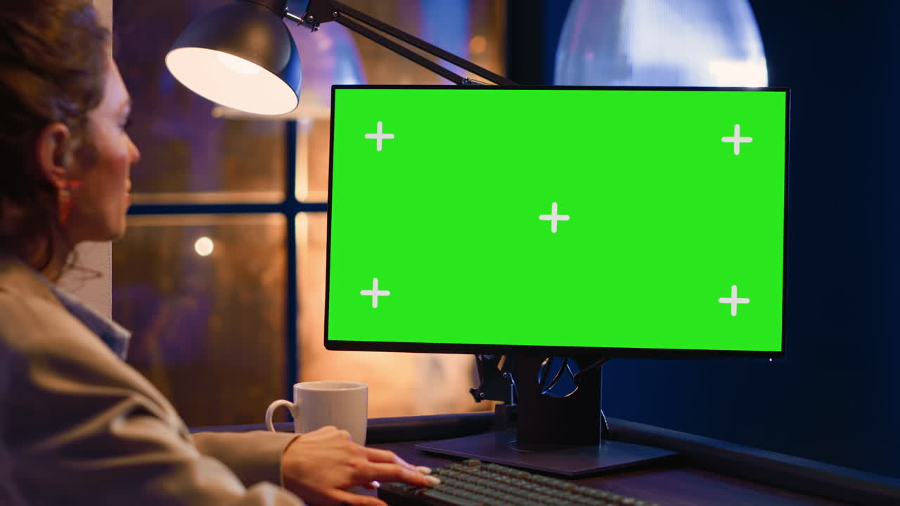 Woman working on a computer with a green screen