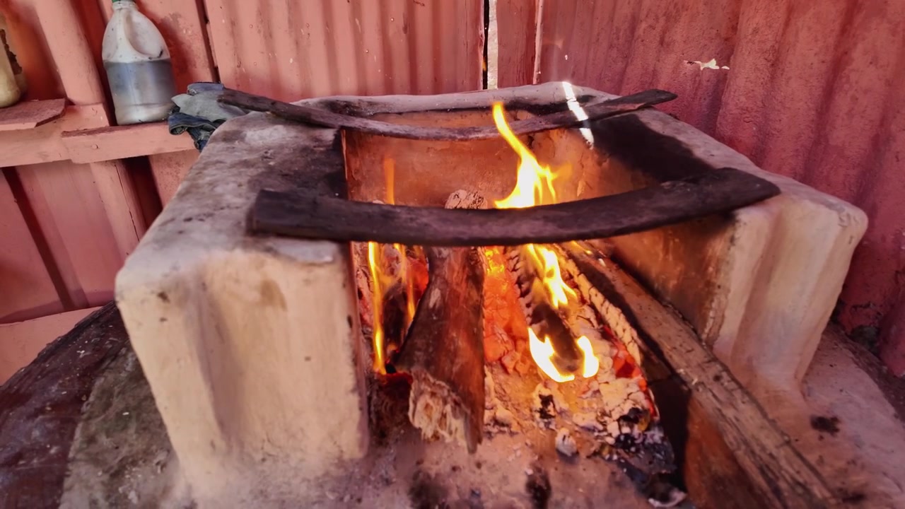Kırsal Dominik kırsalında bir odun sobası çekimi, yanan odundan yükselen alevler, odun ateşinde geleneksel yemek pişirme, otantik, kırsal bir atmosferde.