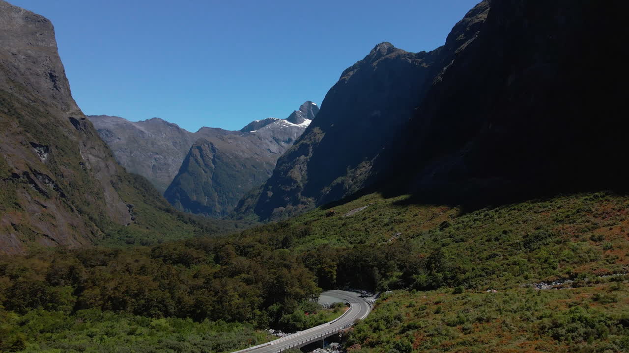 carretera de montaña que asciende por un estrecho valle en fiordland southland, nueva zelanda