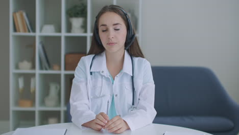 Looking-at-the-camera-listening-woman-doctor-looks-at-the-camera-and-listens-to-the-patient.-A-video-conference-listener.-Portrait-of-a-doctor