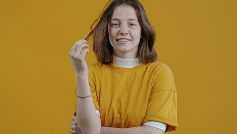 woman adjusting hair in a yellow shirt