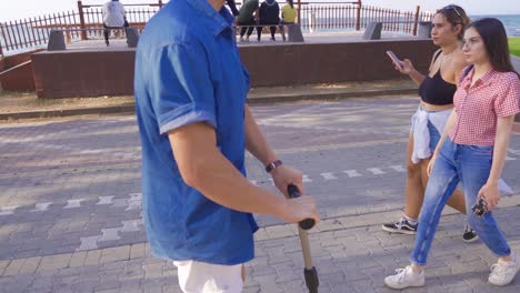 un joven monta un scooter en la playa.
