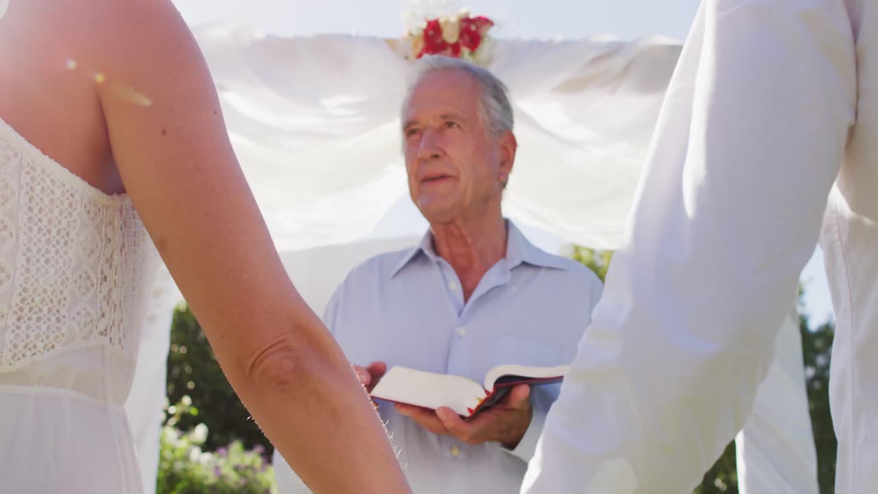 백인 신부 와 신랑 이 의식 중 결혼식 의 담당자 와 함께 야외 제단 에 서 있다