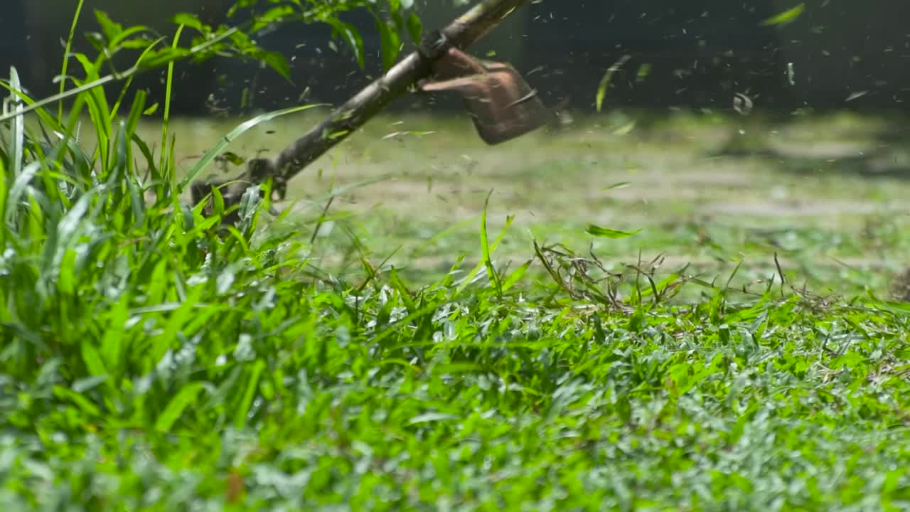 operando un clip de cámara lenta de la máquina desbrozadora, hierba recortada volando por todo el lugar