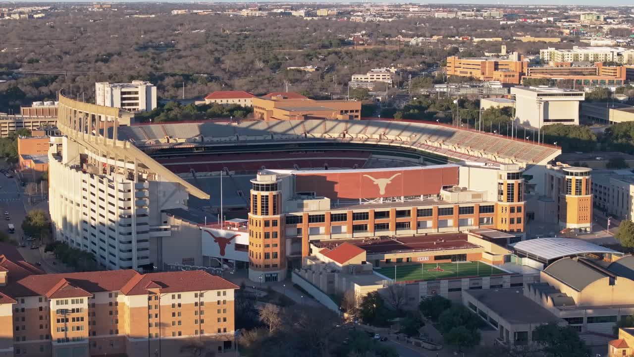 A wide drone shot dollying forward at sunset panning right and revealing the Longhorns logo on the empty Darrell K Royal Texas Memorial Stadium at the University of Texas (UT) in Austin
