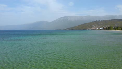 Shallow-water-of-Ohrid-lake-with-colorful-surface-and-birds-flying-near-shoreline