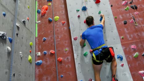 man practicing rock climbing in fitness studio 4k