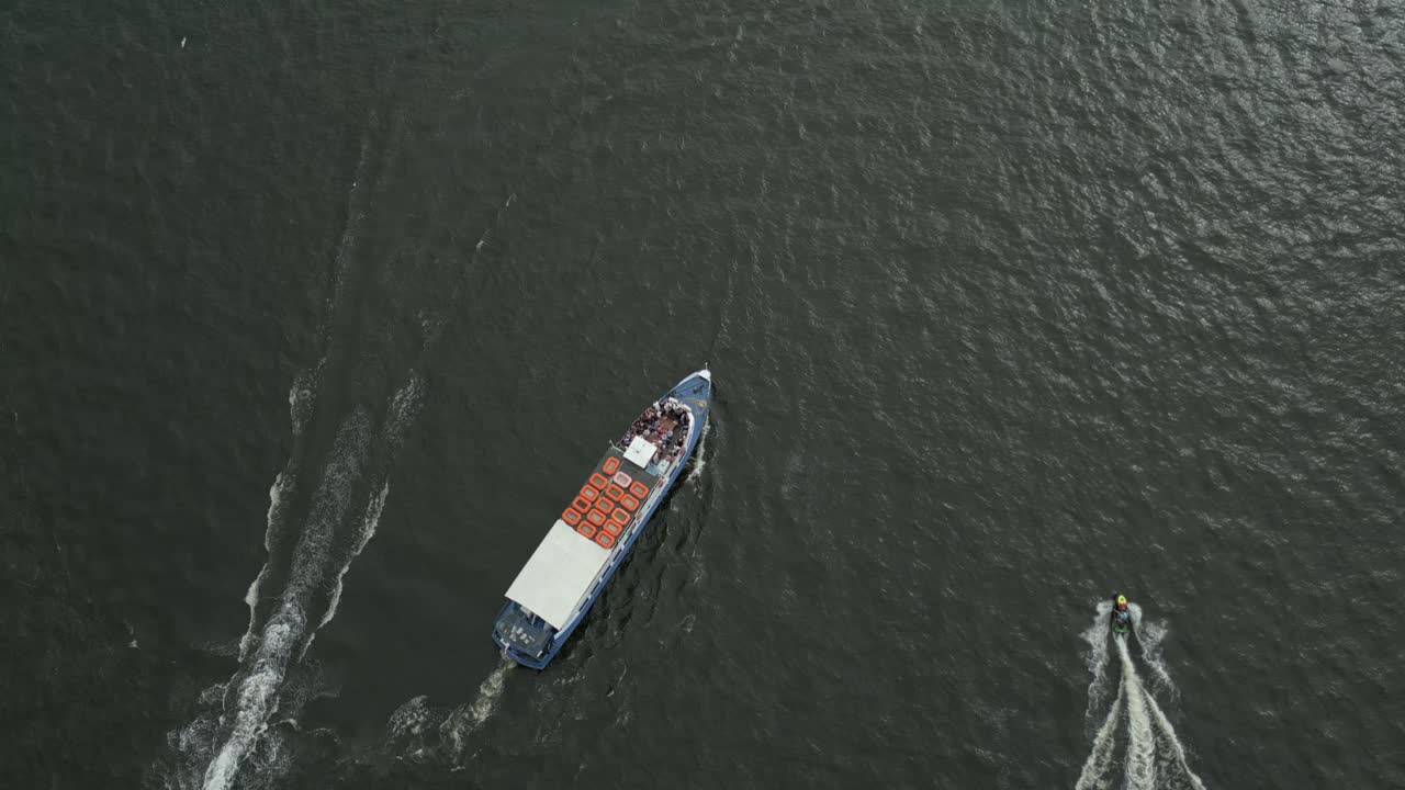 A cargo boat travels across calm water, seen from above on an overcast day
