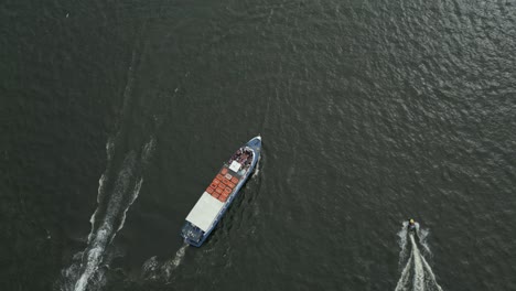 a cargo boat travels across calm water, seen from above on an overcast day