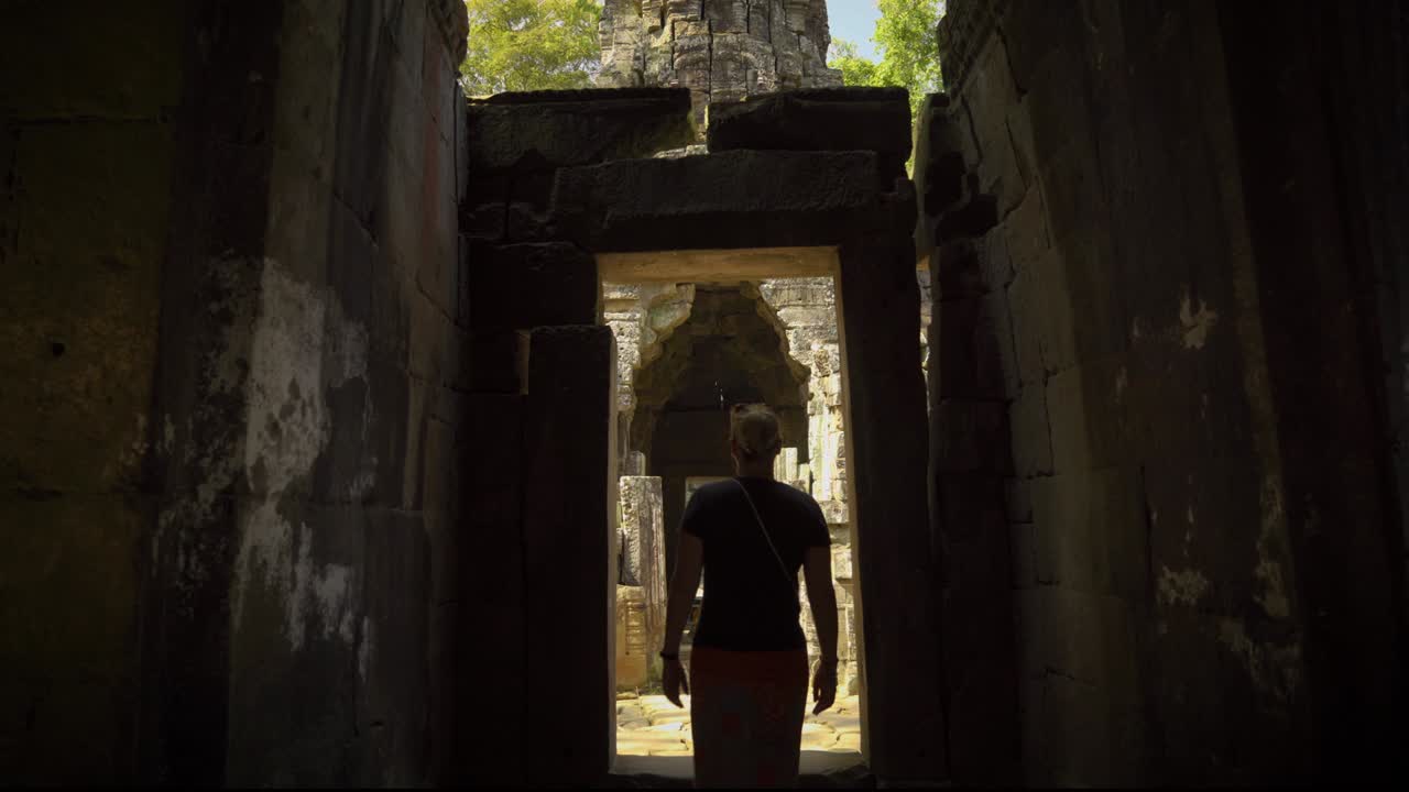 vista trasera de una mujer adulta caucásica explorando el interior del complejo de angkor wat, siem reap, camboya