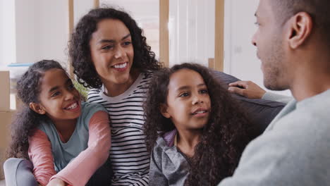 family taking a break and sitting on sofa celebrating moving into new home together