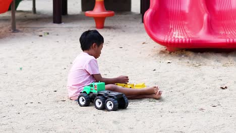 young boy enjoys playing with a toy truck in a sandbox