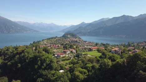 Volar-Sobre-Un-Pequeño-Pueblo-Cerca-De-Un-Lago-En-La-Zona-Montañosa-De-Los-Alpes-Italianos,-Bellagio,-Lago-Di-Como,-Italia