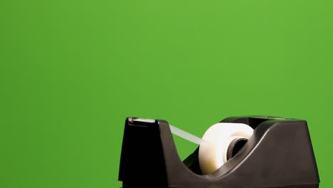 Tape-dispenser,-dispensing-a-piece-of-tape,-on-green-screen