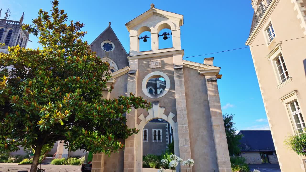 Archway and bell tower of Saint-Pierre church in Changé, Mayenne, France. Low-angle pov