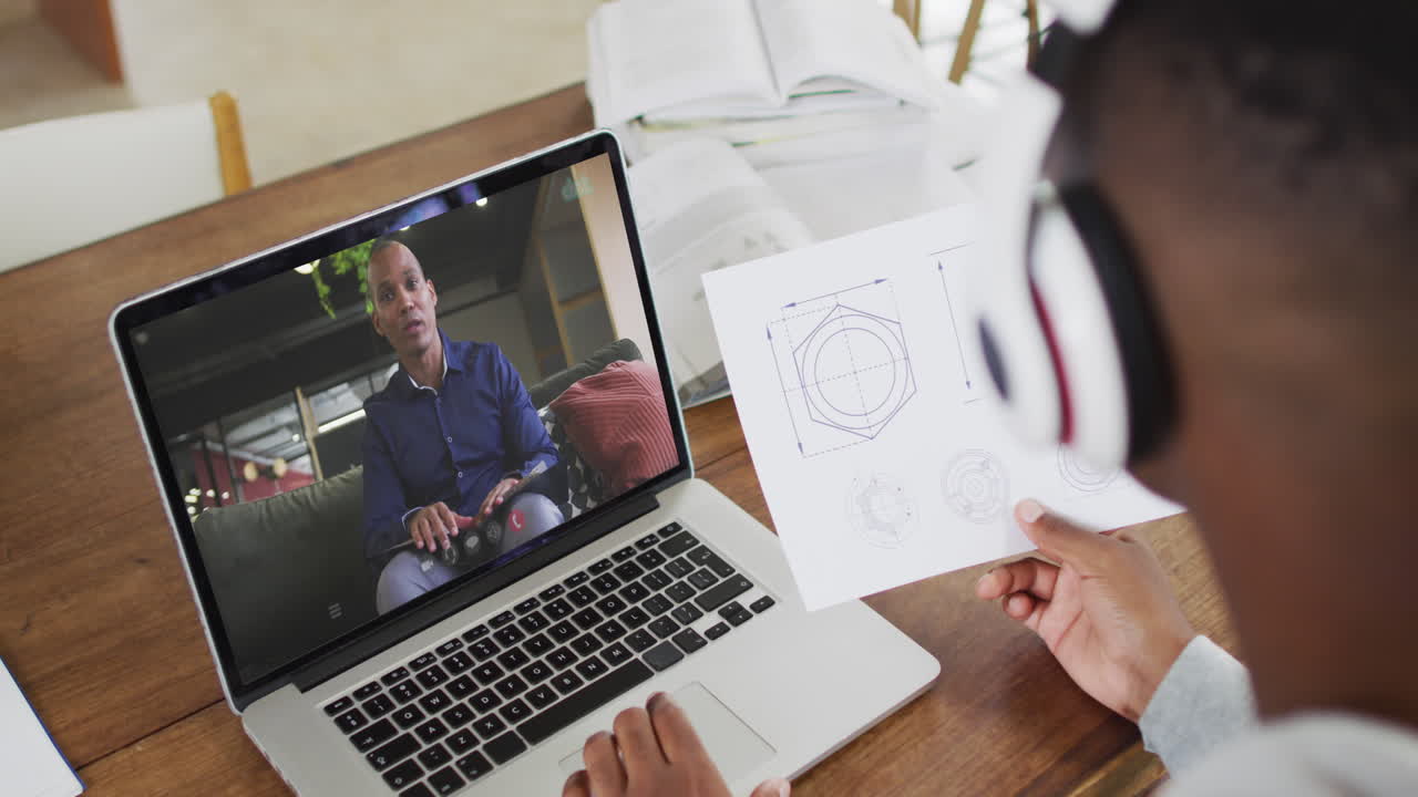 hombre de negocios afroamericano sentado en un escritorio usando una computadora portátil haciendo una videollamada con un colega masculino