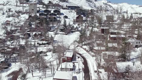 Casas-De-Pueblo-De-Montaña-En-La-Estación-De-Esquí-De-Farellones-De-La-Cordillera-Andina,-Drones-Aéreos-Sobre-Tejados-Nevados-Cerca-De-Santiago-De-Chile