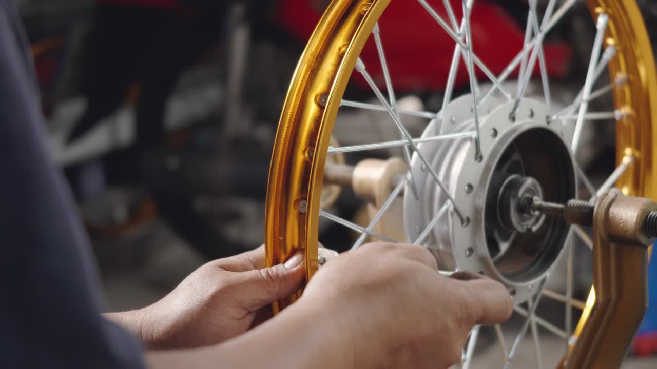 técnico hombre trabajando rueda de motocicleta tiene rayos tejer en herramienta mecánica nueva rueda de acero